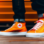 A pair of bright orange, neon sneakers on a wooden floor