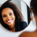A smiling woman looking in the mirror and embracing her reflection